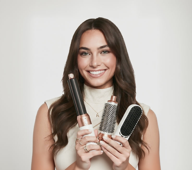Frau zeigt drei Aufsätze der Hyeton 5-in-1 Warmluftbürste: Lockenaufsatz, Volumenbürste und Glättbürste in Weiß-Gold